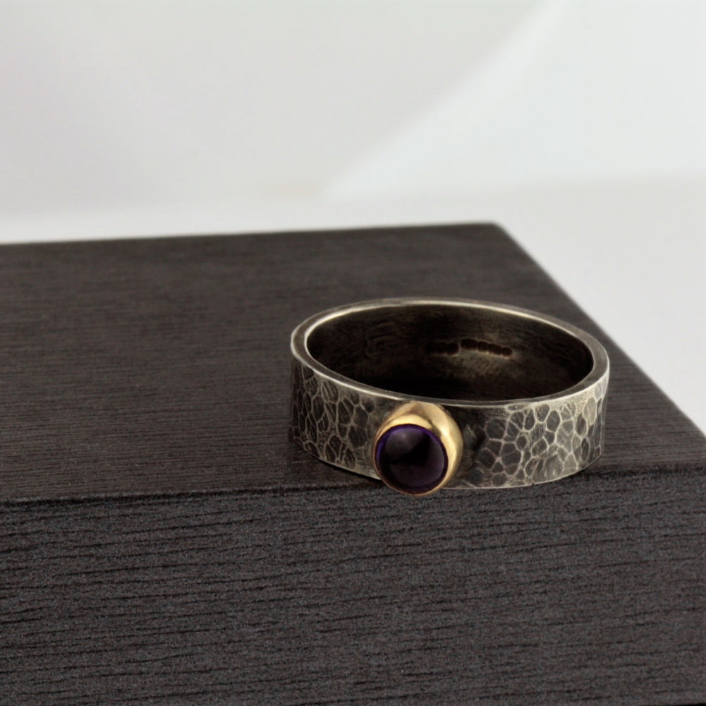 Amethyst set in 9ct gold on a wide hammered silver blossom ring
