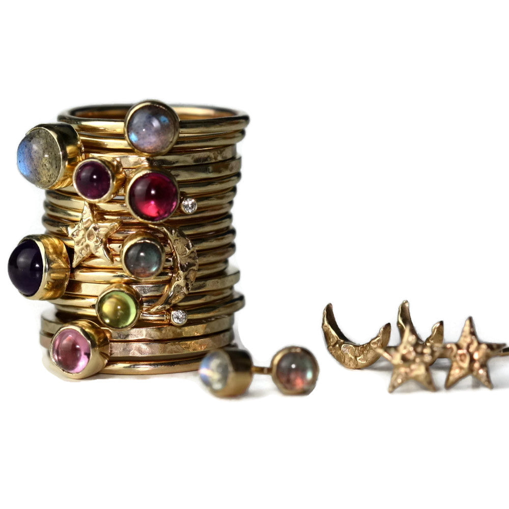 Mixed up stack of solid gold star and moon universe rings and wildflower gemstone rings