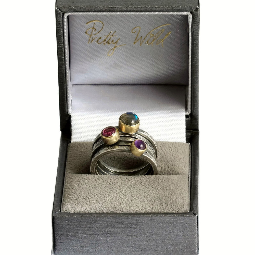 Pretty Wilds branded ring box featuring a full stack of silver and gold blossom stacking rings